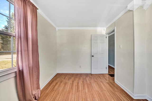 spare room featuring light hardwood / wood-style floors, crown molding, and a wealth of natural light