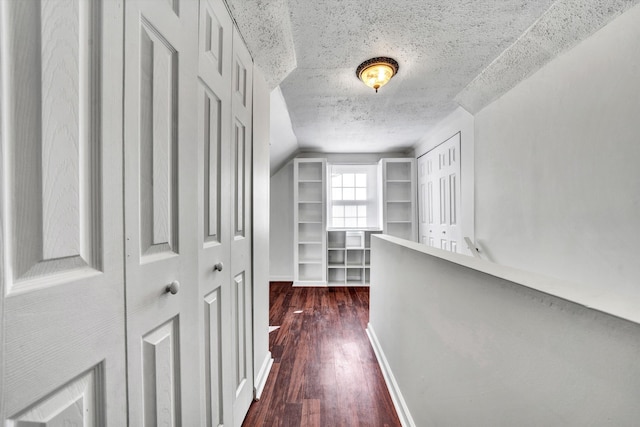 hallway with dark hardwood / wood-style floors, lofted ceiling, and a textured ceiling