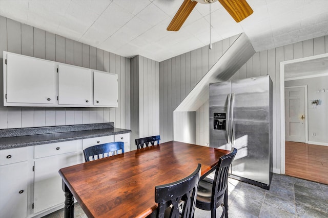 dining room with hardwood / wood-style floors, ceiling fan, and wood walls