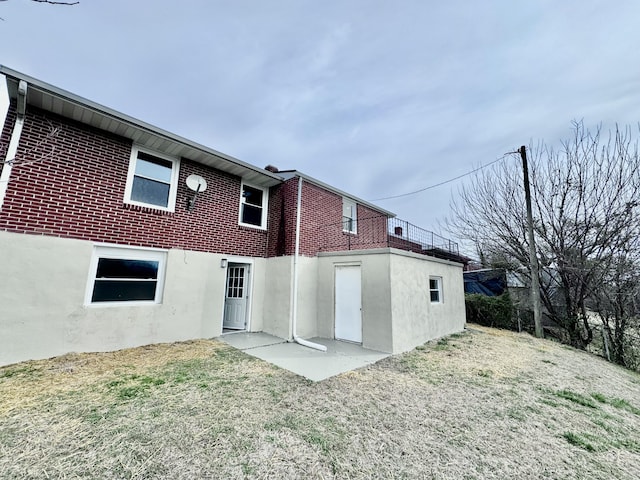 rear view of property featuring brick siding and a yard