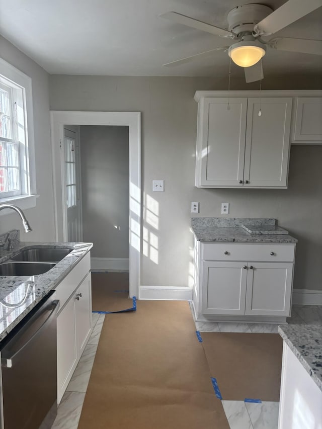 kitchen with white cabinetry, dishwasher, light stone counters, and sink