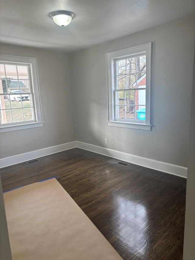 spare room featuring dark hardwood / wood-style flooring and plenty of natural light