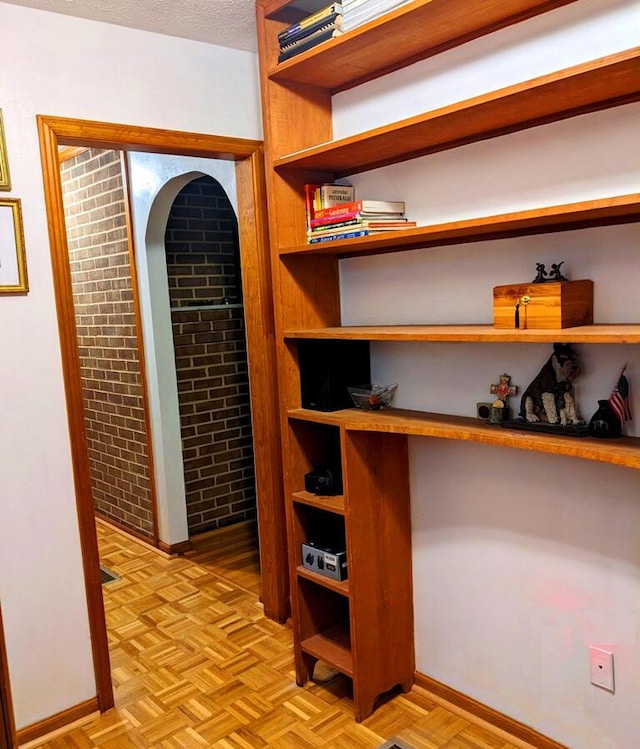 wine area with light parquet floors, brick wall, and a textured ceiling