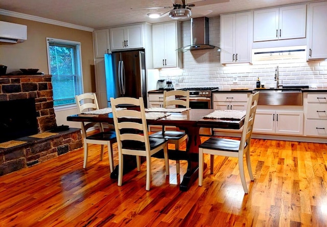 kitchen with white cabinets, wall chimney range hood, and appliances with stainless steel finishes