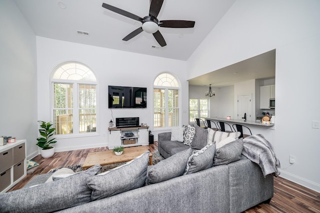 living room featuring high vaulted ceiling, dark hardwood / wood-style floors, ceiling fan with notable chandelier, and a wealth of natural light