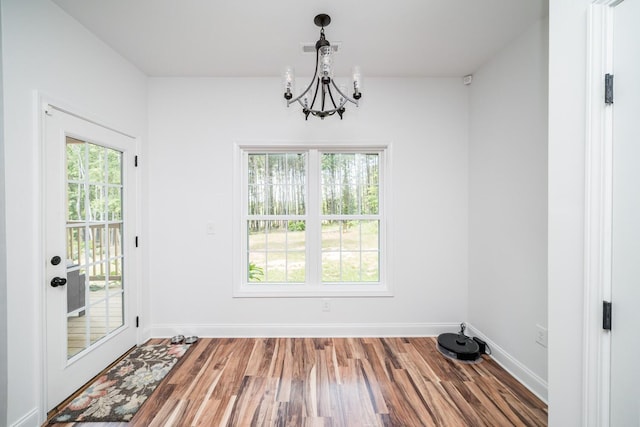 unfurnished dining area featuring a notable chandelier and hardwood / wood-style flooring