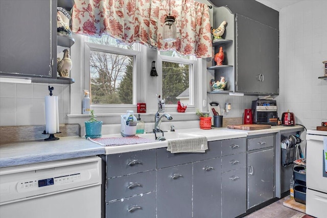 kitchen featuring white dishwasher, light hardwood / wood-style floors, gray cabinetry, and tasteful backsplash