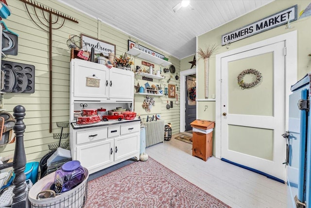 kitchen featuring white cabinets, light hardwood / wood-style floors, and wooden walls