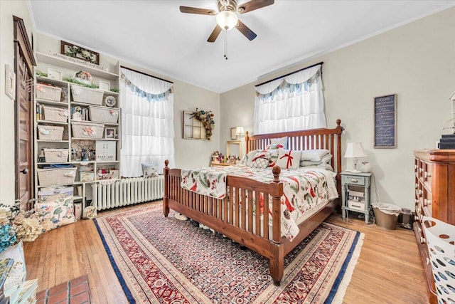 bedroom featuring radiator, ceiling fan, crown molding, and light hardwood / wood-style floors