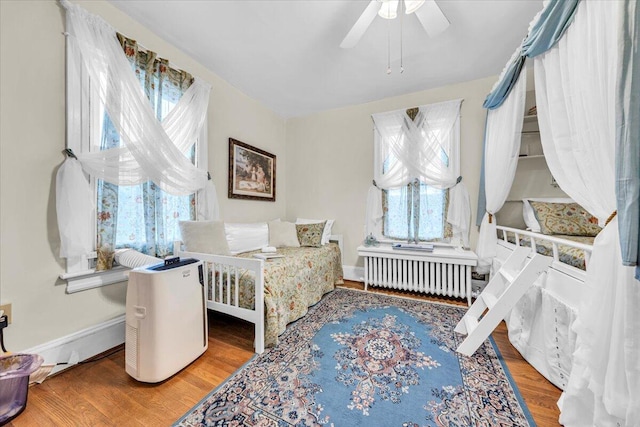 bedroom with radiator, hardwood / wood-style flooring, and ceiling fan