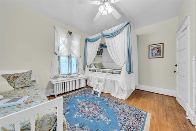 bedroom featuring hardwood / wood-style floors, ceiling fan, and radiator heating unit