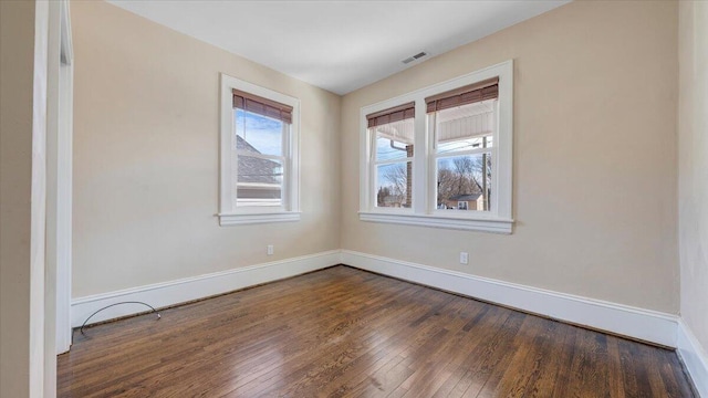 empty room featuring baseboards, visible vents, and dark wood-type flooring