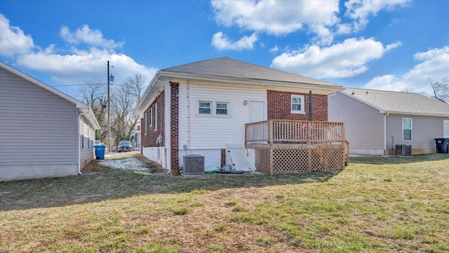 back of property featuring brick siding, a lawn, a deck, and central air condition unit