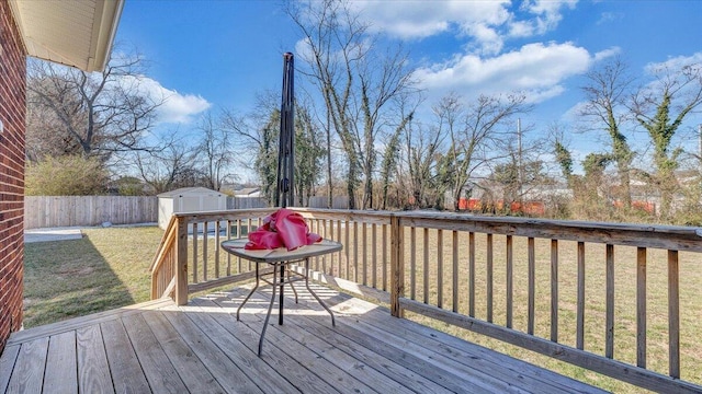 wooden deck featuring an outbuilding, a fenced backyard, a yard, and a storage unit