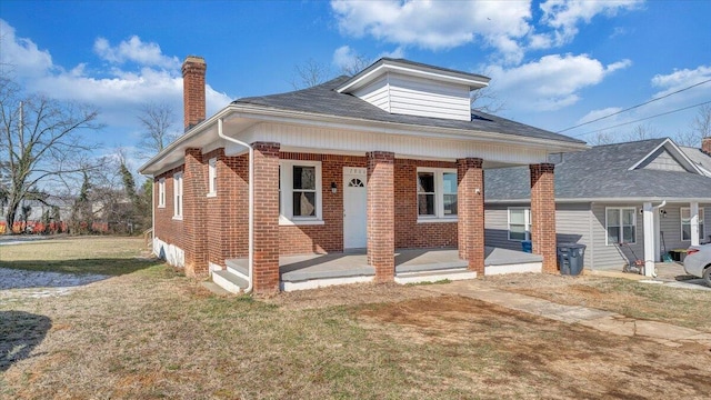 bungalow-style house with brick siding, a chimney, and a front lawn