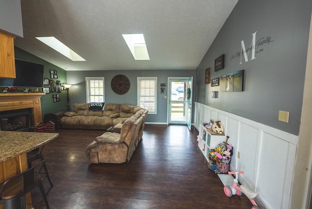 living room with dark hardwood / wood-style floors and vaulted ceiling with skylight