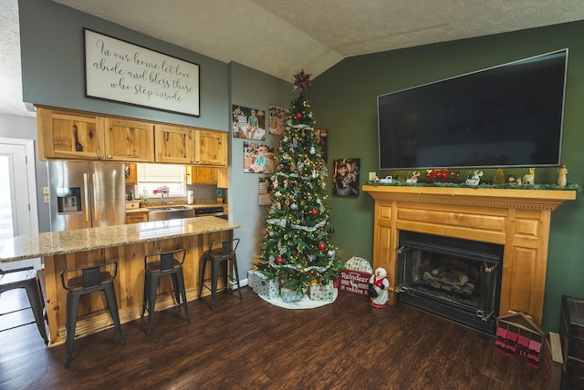 kitchen with stainless steel fridge with ice dispenser, a breakfast bar, dark hardwood / wood-style floors, and lofted ceiling