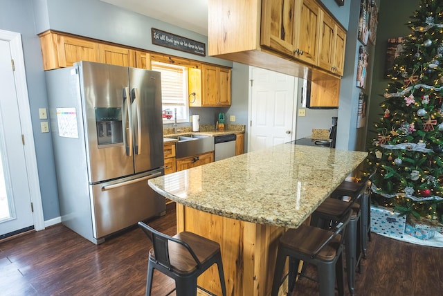 kitchen featuring light stone countertops, sink, stainless steel appliances, dark hardwood / wood-style flooring, and a breakfast bar area