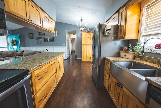 kitchen featuring dark wood-type flooring, an inviting chandelier, vaulted ceiling, a textured ceiling, and stainless steel appliances