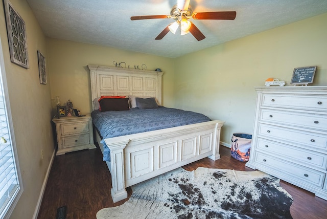 bedroom with a textured ceiling, ceiling fan, and dark wood-type flooring