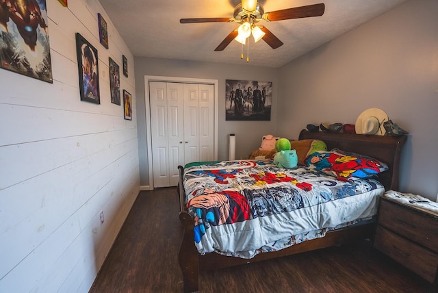 bedroom with wooden walls, ceiling fan, a textured ceiling, dark hardwood / wood-style flooring, and a closet