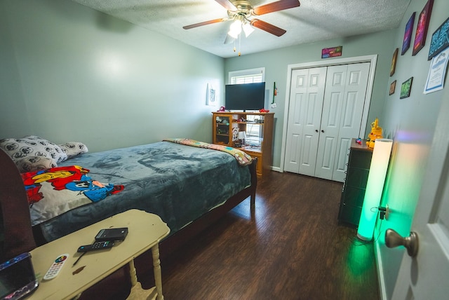 bedroom with a textured ceiling, a closet, ceiling fan, and dark wood-type flooring