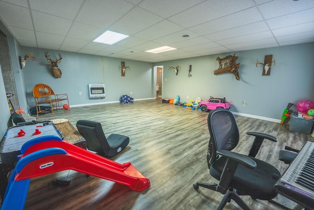 rec room with heating unit, a paneled ceiling, and hardwood / wood-style floors