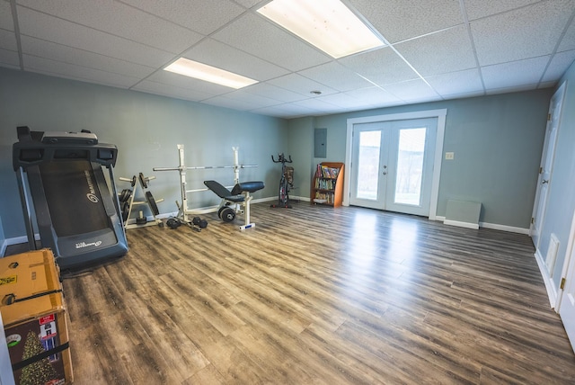 exercise room with dark hardwood / wood-style floors, a drop ceiling, electric panel, and french doors