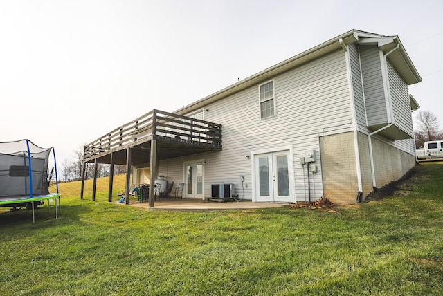 rear view of property featuring a trampoline, french doors, a yard, central AC, and a patio area