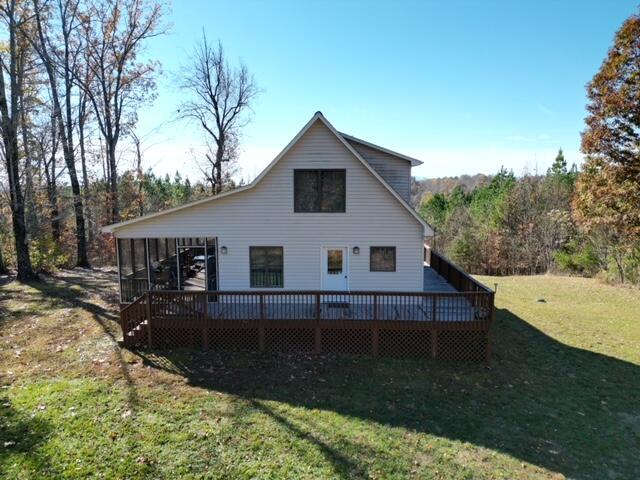 back of house featuring a lawn, a wooden deck, and a sunroom