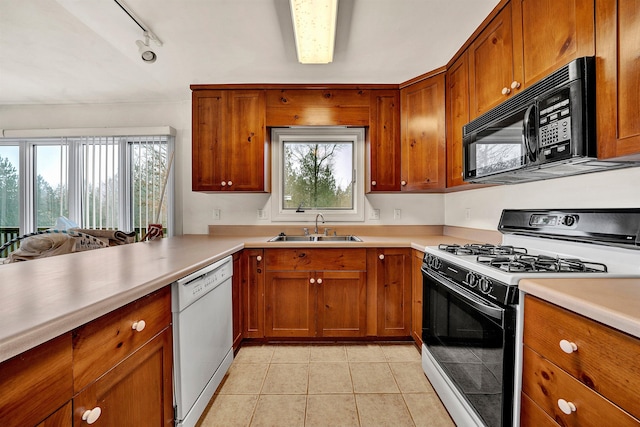 kitchen featuring sink, kitchen peninsula, track lighting, white appliances, and light tile patterned floors