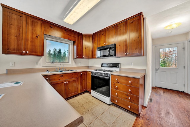 kitchen featuring light hardwood / wood-style floors, white gas range, and sink