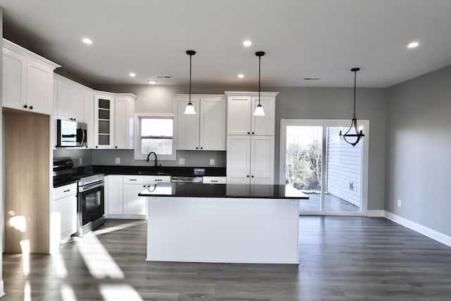 kitchen featuring a center island, white cabinets, hanging light fixtures, and appliances with stainless steel finishes