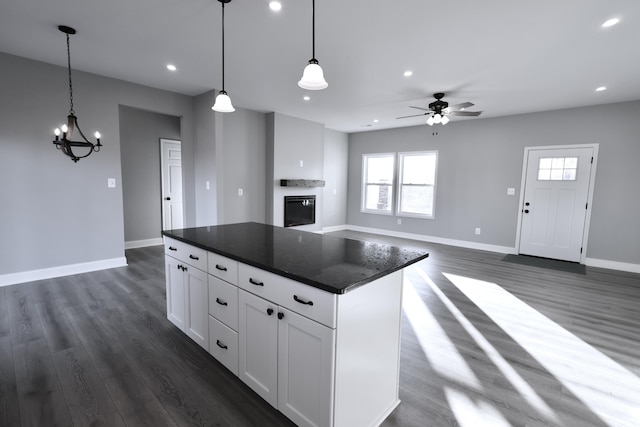 kitchen with a center island, ceiling fan with notable chandelier, dark hardwood / wood-style floors, decorative light fixtures, and white cabinetry