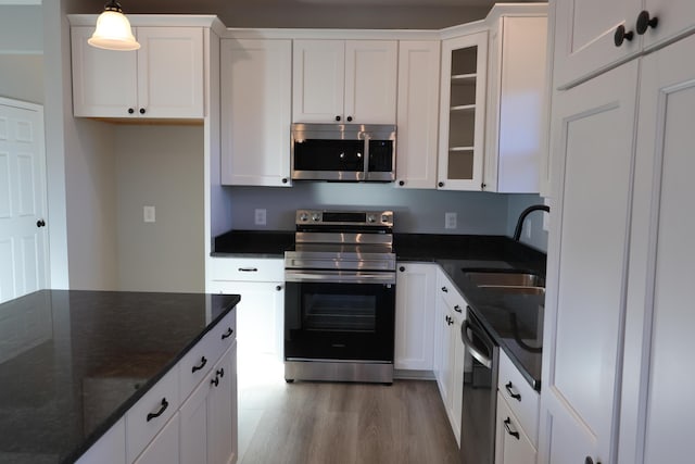 kitchen with white cabinetry, sink, stainless steel appliances, and decorative light fixtures