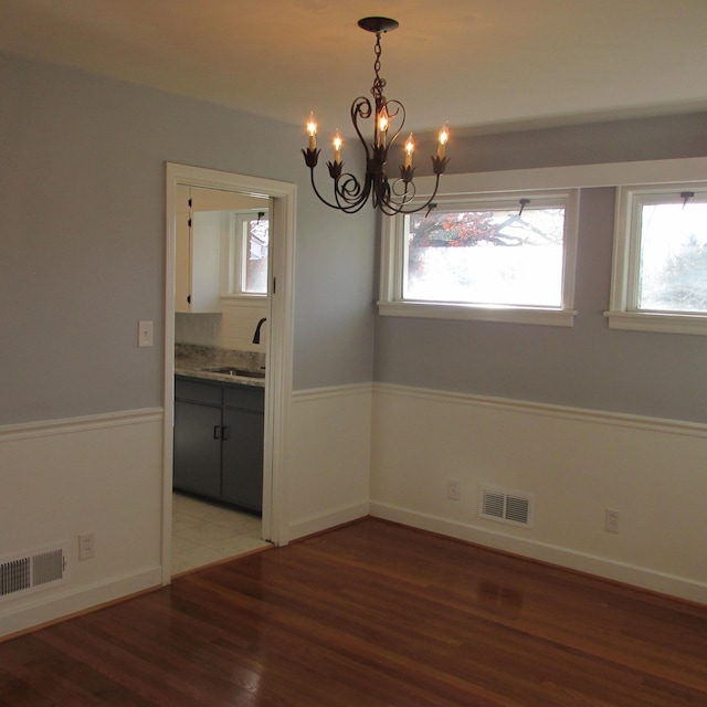 unfurnished dining area with hardwood / wood-style floors, a notable chandelier, and sink