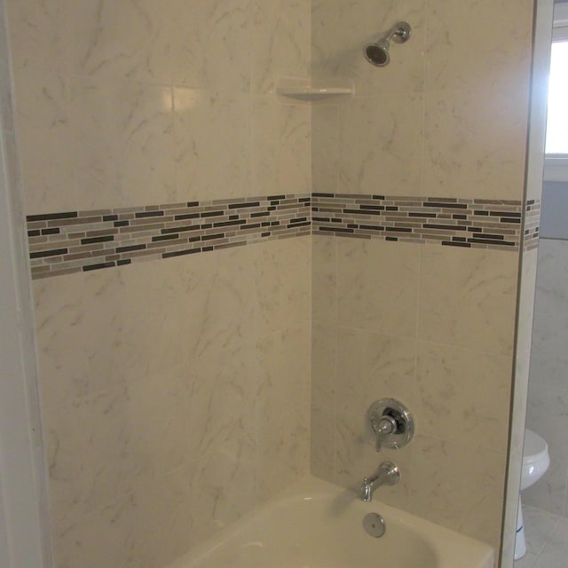 bathroom featuring toilet and tiled shower / bath