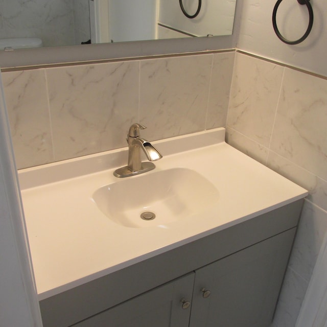 bathroom with backsplash, vanity, toilet, and tile walls