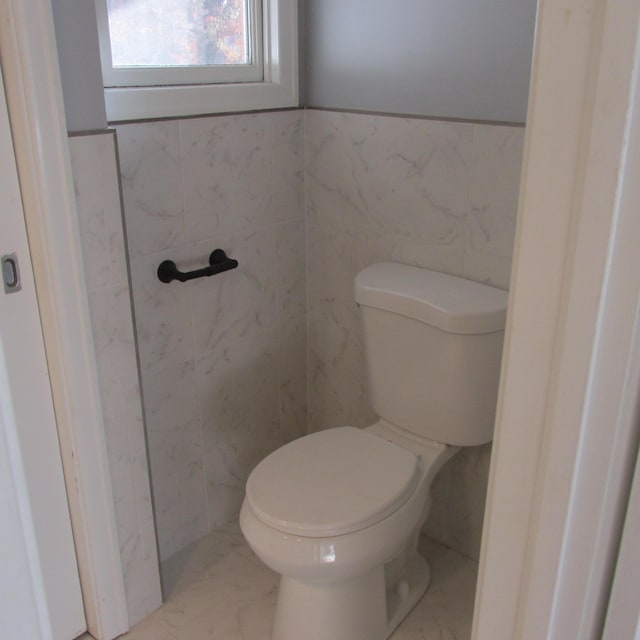 bathroom featuring toilet and tile walls