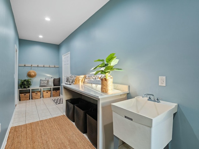 clothes washing area featuring light tile patterned flooring and sink