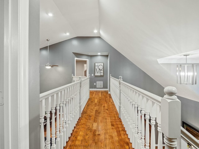 corridor featuring a chandelier, wood-type flooring, and lofted ceiling