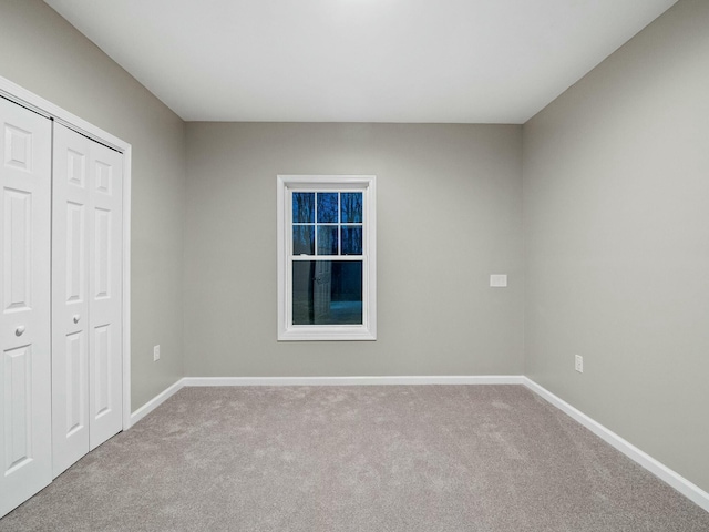 unfurnished bedroom with light colored carpet and a closet