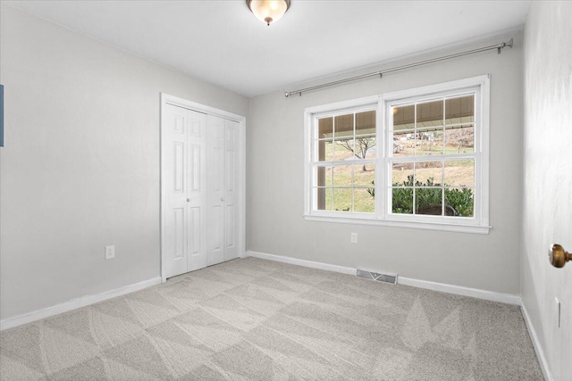 unfurnished bedroom with a closet, multiple windows, carpet flooring, and visible vents