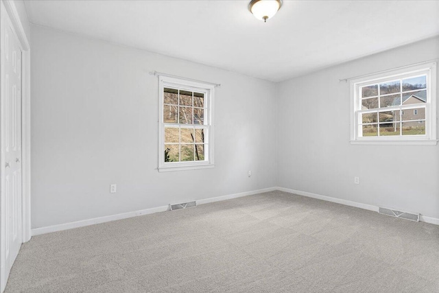 unfurnished room with a wealth of natural light, carpet, and visible vents