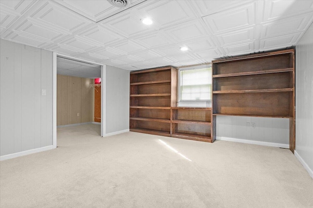 below grade area featuring an ornate ceiling, wooden walls, baseboards, and carpet flooring