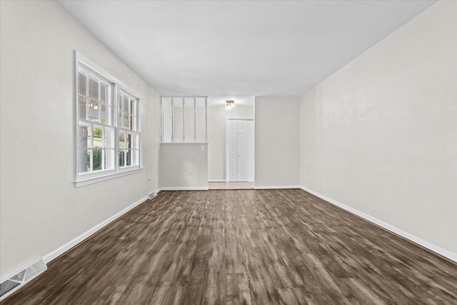 empty room featuring baseboards, visible vents, and dark wood-type flooring