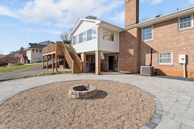 rear view of house with central AC, brick siding, stairs, a chimney, and a patio area