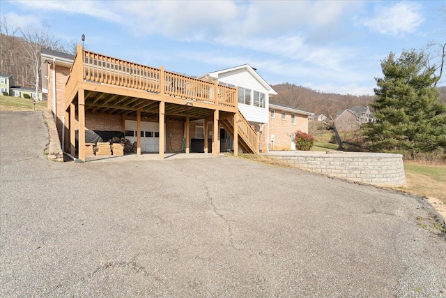 view of front facade featuring a deck, stairway, aphalt driveway, and brick siding