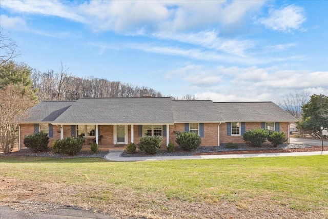 ranch-style home with covered porch, brick siding, a front lawn, and roof with shingles