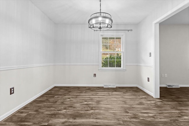 unfurnished dining area with visible vents, a chandelier, and wood finished floors